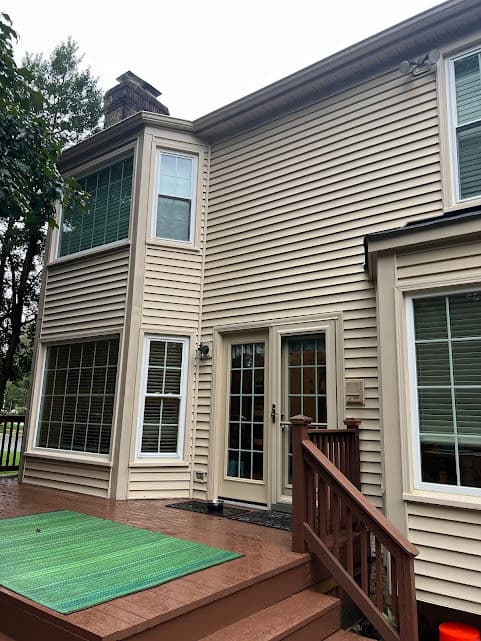 Two-story house with large windows and greenery in front under a cloudy sky.