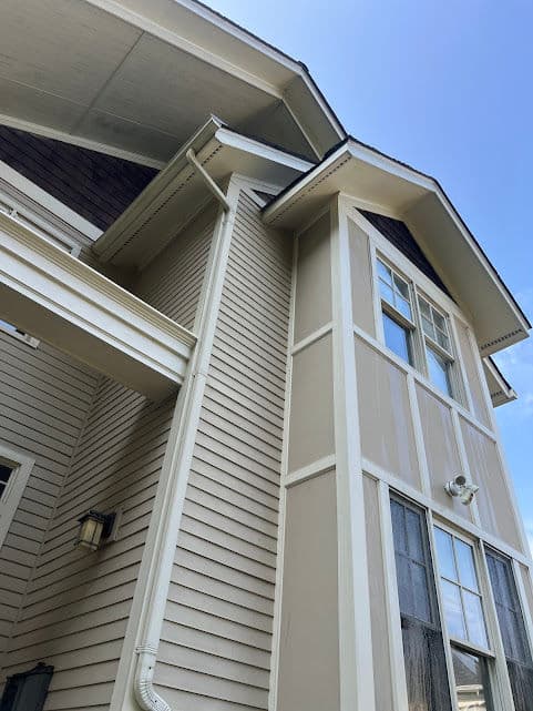 Modern house exterior featuring vertical siding, large windows, and a blue sky.