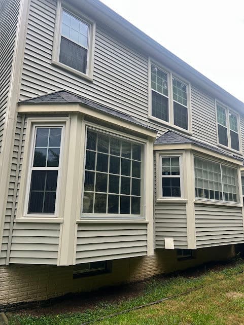 Modern house exterior with large bay windows and vinyl siding, showcasing architectural design.