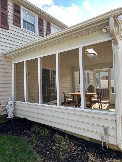Sunroom with a dining table and chairs, surrounded by large windows and outdoor views.