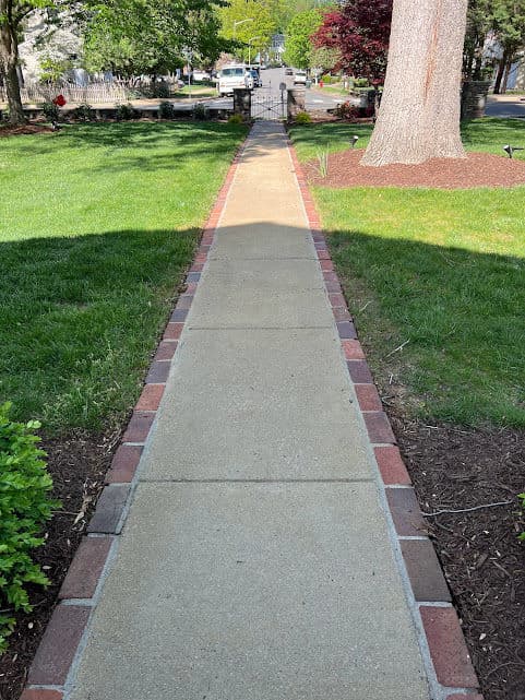 Pathway leading through a landscaped garden with brick borders and a view of the entrance gate.
