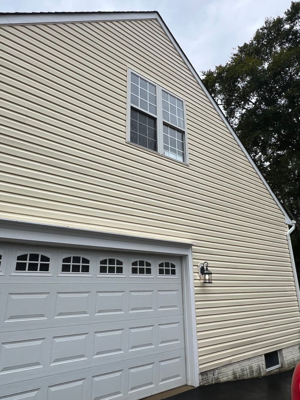 House exterior with beige siding and a large window above a garage door.